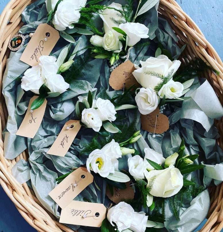 A basket of single white rose buttonholes